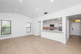 Located at 9940 Robbins Dr in Beverly Hills, CA, this thoughtfully designed single-floor unit offers a clean, modern aesthetic with high-quality finishes throughout. Light hardwood flooring runs continuously across all rooms, complementing the crisp white walls and recessed lighting that create a bright, airy ambiance.

The open-concept kitchen and living area serves as the heart of the unit. The kitchen is well-appointed with white shaker cabinetry extending to the ceiling, quartz countertops, a neutral subway tile backsplash with under-cabinet lighting, and a full suite of stainless steel appliances including a gas range, dishwasher, and French door refrigerator. A breakfast bar provides a seamless transition into the living area, which features a vaulted, arched ceiling that lends an elevated sense of space.

Two bright rooms are filled with natural light from multiple windows fitted with white horizontal blinds. One room opens to an outdoor balcony through full-height glass French doors with views of the surrounding tree-lined neighborhood. Three closets — including one with built-in shelving and drawers — provide generous storage throughout.

The bathroom is finished with floor-to-ceiling vertical tile in the walk-in glass shower, hexagonal mosaic tile flooring, and a window for natural ventilation. Two hallways connect the spaces efficiently, completing this well-planned Beverly Hills residence.