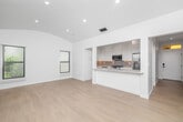 Located at 9940 Robbins Dr in Beverly Hills, CA, this thoughtfully designed single-floor unit offers a clean, modern aesthetic with high-quality finishes throughout. Light hardwood flooring runs continuously across all rooms, complementing the crisp white walls and recessed lighting that create a bright, airy ambiance.

The open-concept kitchen and living area serves as the heart of the unit. The kitchen is well-appointed with white shaker cabinetry extending to the ceiling, quartz countertops, a neutral subway tile backsplash with under-cabinet lighting, and a full suite of stainless steel appliances including a gas range, dishwasher, and French door refrigerator. A breakfast bar provides a seamless transition into the living area, which features a vaulted, arched ceiling that lends an elevated sense of space.

Two bright rooms are filled with natural light from multiple windows fitted with white horizontal blinds. One room opens to an outdoor balcony through full-height glass French doors with views of the surrounding tree-lined neighborhood. Three closets — including one with built-in shelving and drawers — provide generous storage throughout.

The bathroom is finished with floor-to-ceiling vertical tile in the walk-in glass shower, hexagonal mosaic tile flooring, and a window for natural ventilation. Two hallways connect the spaces efficiently, completing this well-planned Beverly Hills residence.