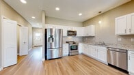 Located at 4866 Fulton Dr NW in Canton, Ohio, this single-floor home offers a clean, modern design with consistent finishes throughout. The kitchen is a standout feature, showcasing crisp white shaker-style cabinetry, granite-look countertops, and a full suite of stainless steel appliances including a French door refrigerator, gas range, over-the-range microwave, and dishwasher. Light hardwood flooring runs through the main living areas, complementing the neutral warm-toned walls and recessed lighting overhead. A pendant light adds a refined touch above the kitchen workspace. The open-concept layout connects the kitchen seamlessly to the living and dining area, which benefits from sliding glass door access and additional windows that invite natural light. A well-lit hallway connects the main living spaces to the private rooms, which feature plush carpeting and organized closet systems. The bathrooms are finished with white cabinetry, granite-patterned countertops, and light tile flooring, maintaining the home's cohesive aesthetic. A dedicated laundry area with a full-size washer and dryer adds practical convenience. Overall, this home presents a move-in-ready, well-appointed space with thoughtful design details throughout.