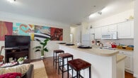 This well-appointed 3-bedroom, 3-bathroom single-story home offers a thoughtfully designed layout that balances comfort and functionality. The open-concept kitchen is outfitted with white cabinetry, white appliances, and a curved breakfast bar with seating for multiple bar stools, making it ideal for casual dining and entertaining. Track lighting overhead adds a modern touch, while wood-look flooring flows throughout the main living areas.

The living room is generously sized, featuring crown molding, multiple windows dressed with floor-length curtains that invite ample natural light, and warm wood-look flooring that anchors the space. A hallway connects the main living areas to the bedrooms, each of which is carpeted for comfort and includes windows with curtain treatments that provide privacy and soft light.

Each bathroom is clean and functional, featuring white vanity cabinetry, well-lit mirrors, and tile flooring. At least one bathroom includes direct access to a walk-in closet with wire shelving, providing practical storage solutions.

A dedicated laundry room houses a full-size washer and dryer alongside a water heater, adding everyday convenience. The home's cohesive neutral palette and crown molding details throughout contribute to a polished, move-in-ready atmosphere.