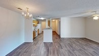 Located at 22 Wood, this single-story residence offers a well-organized layout designed for comfortable everyday living. The open-concept living and dining area is anchored by dark wood-look laminate flooring and features a chandelier that adds a touch of elegance. French doors flood the living space with natural light while providing outdoor access. A ceiling fan enhances airflow throughout the room.

The galley-style kitchen is efficiently arranged with warm honey-toned cabinetry lining both walls, offering generous storage and laminate countertops. White appliances, including an electric coil range and refrigerator, are complemented by a built-in range hood. A peninsula counter connects the kitchen to the living area, creating a natural flow between spaces.

The bedrooms are carpeted for comfort, each equipped with ceiling fans and ample natural light. One bedroom features a large window with outdoor views, while another offers a quieter, more enclosed setting.

Two full bathrooms include tub-shower combinations with chrome fixtures and safety grab bars. Wood-look flooring, white surrounds, and textured ceilings maintain a consistent, clean aesthetic. The overall ambiance is neutral, bright, and move-in ready.