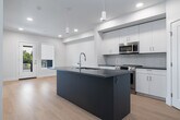 This thoughtfully designed one-bedroom, one-bathroom unit in Meridian, Idaho offers a clean, modern aesthetic with an efficient and well-organized layout. Light wood-style flooring flows throughout the space, complementing the crisp white walls and creating a bright, cohesive feel.

The open-concept kitchen and living area serves as the heart of the unit. The kitchen features a central island with a dark quartz-style countertop, an undermount sink, and a bold blue base — a striking design detail. White upper and lower cabinetry extends along the wall, accented by a classic subway tile backsplash and dark countertops. Stainless steel appliances, including a range, over-the-range microwave, dishwasher, and refrigerator, complete the modern kitchen. Pendant lighting and recessed ceiling lights provide ample illumination.

The adjacent living area is open and airy, benefiting from natural light through a glass door and window that lead to an outdoor access point, adding a sense of connection to the exterior.

The bedroom is a calm, neutral retreat with two windows dressed in roller shades, allowing for natural light control. It includes access to a dedicated closet with built-in shelving.

The bathroom is clean and functional, offering a full tub-shower combination, a white vanity with dark countertop, and a lighted mirror — all finished in a consistent, contemporary style.