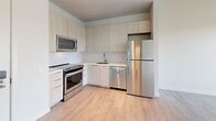 Located at 5522 Baum Blvd in Pittsburgh's Shadyside neighborhood, this one-bedroom, one-bathroom unit offers a thoughtfully designed layout with clean, contemporary finishes throughout. The open-concept kitchen and living area serves as the heart of the space, featuring light wood-tone cabinetry that extends to the ceiling for ample storage, stainless steel appliances including a refrigerator, dishwasher, range, and over-the-range microwave, and light hardwood flooring that runs throughout. A large floor-to-ceiling window floods the living area with natural light and frames elevated views of the surrounding Pittsburgh skyline and treetops. An exposed concrete ceiling detail above the living area adds an industrial design element that contrasts stylishly with the otherwise clean white walls and modern finishes. The bedroom is a calm, minimalist retreat with light hardwood floors, crisp white walls, and a double-door closet offering generous storage. The bathroom is finished with large-format neutral tile, a frameless glass walk-in shower with a rainfall showerhead, and polished chrome fixtures. A utility room and additional unclassified space round out the floor plan, providing practical functionality.