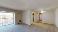 This single-floor residence offers a practical and comfortable layout designed for everyday living. The open living area is carpeted throughout and filled with natural light, anchored by a sliding glass door that leads to a private balcony overlooking the surrounding neighborhood. A ceiling fan adds comfort to the space, and a wall-mounted HVAC vent provides efficient climate control.

The kitchen is well-appointed with rich, dark wood cabinetry, stone-look laminate countertops, a stainless steel sink, a dishwasher, and a stainless steel refrigerator and range. A window above the sink brings in natural light, making the kitchen bright and functional.

The bedrooms are carpeted and generously sized, each featuring neutral walls and windows that allow natural light to fill the rooms. At least one bedroom includes a built-in closet with shelving, providing organized storage space.

The residence includes two bathrooms. The full bathroom features a tub-shower combination with white tile surround and light tile flooring. The half or secondary bathroom is finished with tile flooring, a navy blue vanity with a white countertop, a wall mirror, and a multi-bulb vanity light fixture.

A carpeted hallway connects the living areas to the bedrooms and bathrooms, creating a cohesive and easy-to-navigate floor plan throughout the home.