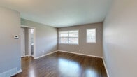 Located at 4015 Summer Ave in Memphis, Tennessee, this two-bedroom, one-bathroom unit offers a practical and well-maintained single-floor layout. Rich, dark hardwood flooring runs throughout the main living areas and both bedrooms, providing a warm and cohesive aesthetic against the neutral gray walls and crisp white trim and baseboards. The spacious primary bedroom receives generous natural light through a large double-pane window fitted with blinds, offering views of the surrounding greenery. The second bedroom mirrors this layout with its own window, hardwood floors, and ample wall space. The kitchen is equipped with white shaker-style cabinetry, light tile flooring, and a full-size black refrigerator, providing functional storage and prep space. The bathroom features a full tub and shower combination with clean white surround panels and a window that brings in natural light. A connecting hallway ties the rooms together efficiently, contributing to the unit's straightforward and accessible flow. The overall interior presents a clean, move-in-ready condition with consistent finishes throughout, making it a practical residential option in the Summer Avenue corridor of Memphis.