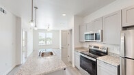 Located at 2817 Andover St in Jefferson, Louisiana, this well-designed 2-bedroom, 1-bathroom residence offers a clean, modern aesthetic throughout its single-floor layout. The open-concept kitchen serves as the heart of the home, anchored by a peninsula with granite countertops and an integrated sink, illuminated by stylish pendant lighting. Gray shaker-style cabinetry pairs seamlessly with a full suite of stainless steel appliances, including a refrigerator, electric range, and over-the-range microwave. Light hardwood-style flooring flows continuously through the kitchen, living area, and bedrooms, creating a cohesive and bright atmosphere. Both bedrooms are comfortably sized, each featuring ceiling fans and large windows that invite abundant natural light and offer views of the surrounding neighborhood. The spacious primary bedroom provides ample room for furnishings. The full bathroom is finished with a granite-topped vanity, gray shaker cabinetry, a framed mirror, and a tub-shower combination, all set against clean white walls. A hallway connects the rooms efficiently, and the overall neutral color palette and modern finishes give the space a fresh, move-in-ready feel.