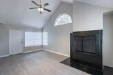 Located at 14135 Champions Dr in Houston, TX 77069, this single-story home offers a well-designed layout with consistent wood-look flooring throughout. The living area is a standout, featuring vaulted ceilings with exposed beams, a ceiling fan, an arched window that invites natural light, and a striking floor-to-ceiling tiled fireplace that serves as a central focal point. The open flow between the living and dining areas creates a sense of spaciousness and connectivity. The kitchen is equipped with white cabinetry, granite-style countertops, a mosaic tile backsplash, and black appliances including a refrigerator, range, microwave, and dishwasher. A peninsula with a breakfast bar provides additional prep space and casual seating, while an adjacent bathroom adds everyday convenience. The bedrooms are comfortably sized, each with ceiling fans, natural light from windows with blinds, and ample closet space. The bathroom features a vanity with a light countertop and cabinetry, connected via a hallway that maintains a clean, neutral aesthetic. Throughout the home, light gray walls and white trim create a bright, cohesive atmosphere that complements the warm tones of the flooring.