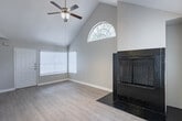 Located at 14135 Champions Dr in Houston, TX 77069, this single-story home offers a well-designed layout with consistent wood-look flooring throughout. The living area is a standout, featuring vaulted ceilings with exposed beams, a ceiling fan, an arched window that invites natural light, and a striking floor-to-ceiling tiled fireplace that serves as a central focal point. The open flow between the living and dining areas creates a sense of spaciousness and connectivity. The kitchen is equipped with white cabinetry, granite-style countertops, a mosaic tile backsplash, and black appliances including a refrigerator, range, microwave, and dishwasher. A peninsula with a breakfast bar provides additional prep space and casual seating, while an adjacent bathroom adds everyday convenience. The bedrooms are comfortably sized, each with ceiling fans, natural light from windows with blinds, and ample closet space. The bathroom features a vanity with a light countertop and cabinetry, connected via a hallway that maintains a clean, neutral aesthetic. Throughout the home, light gray walls and white trim create a bright, cohesive atmosphere that complements the warm tones of the flooring.