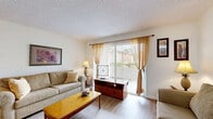 Located at 4398 Rainier Way in Oceanside, California, this single-floor, 3-bedroom, 2-bathroom home offers a well-organized layout designed for comfortable everyday living. The open-concept living room and kitchen area serves as the heart of the home, with light wood-look flooring, neutral walls, and a large sliding glass door dressed in sheer curtains that fills the space with natural light and provides a view of the outdoors. The kitchen features light wood cabinetry, a granite-style countertop with a breakfast bar pass-through, and white appliances including a range, microwave, and refrigerator. The spacious primary bedroom is finished with plush carpeting, a textured ceiling, and a window that allows in natural light. The additional bedrooms also feature carpet flooring, open closet storage, and textured ceilings. Both bathrooms include full tub-and-shower combinations with tile surrounds, wood-look flooring, and window or vanity lighting. A dedicated laundry area and hallway round out the functional floor plan. The home's consistent, warm color palette and practical finishes make it a comfortable residence in the coastal Southern California community of Oceanside.