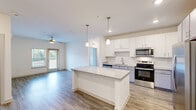 Located at 1300 S Davis Rd in LaGrange, Georgia, this single-floor residence offers a thoughtfully designed layout with two bedrooms, two bathrooms, two closets, and a dedicated laundry room. The open-concept kitchen serves as the heart of the home, boasting white shaker cabinetry, a subway tile backsplash, granite countertops, and a central island with stylish pendant lighting overhead. Stainless steel appliances, including a range, microwave, and refrigerator with ice maker, complete the modern kitchen. Wood-look plank flooring flows throughout the main living areas, lending a clean and contemporary feel, while a ceiling fan in the living room adds comfort. Natural light filters in through windows and a glass door that opens to an outdoor area. The primary bedroom is generously sized and features plush carpeting, a ceiling fan, and direct access to a well-appointed en-suite bathroom with a double-sink granite vanity, a glass-enclosed shower, and wood-look flooring. The second bedroom also features carpet flooring and is served by an additional full bathroom. Closets are equipped with wire shelving for organized storage, and the in-unit laundry room houses a full-size washer and dryer with overhead shelving.