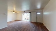 This single-floor residence offers a practical and comfortable layout designed for everyday living. The living room serves as the heart of the home, featuring plush wall-to-wall carpeting, neutral-toned walls, and a ceiling fan that enhances air circulation throughout the space. A full-lite front door with a decorative transom window allows natural light to filter in, while large sliding glass doors open directly to an outdoor patio area, providing seamless indoor-outdoor connectivity and views of surrounding greenery.

The living area flows openly toward the kitchen, which is equipped with warm honey-toned wood cabinetry, laminate countertops, a coil-burner electric range, and a refrigerator — offering ample storage and functional workspace for meal preparation.

The residence includes two carpeted bedrooms, each featuring neutral walls, individual windows with blinds that invite natural light, and ceiling-mounted HVAC vents for climate control. Both rooms offer a quiet, versatile space suitable for a variety of uses.

The bathroom is appointed with a full tub-and-shower surround in crisp white, complemented by richly toned tile flooring that adds a grounded, earthy contrast. A towel bar and standard fixtures complete the space with practical utility.

Overall, this residence presents a straightforward, well-organized floor plan with consistent finishes throughout.