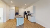 Located at 1810 Highpoint Ave in Richmond, Virginia, this two-story residence offers a clean, contemporary design with a thoughtful layout across both levels. The main floor centers around a well-appointed kitchen featuring stainless steel appliances — including a refrigerator, electric range, and built-in microwave — paired with crisp white cabinetry extending to the ceiling for ample storage. A kitchen island with an integrated sink and gray countertops provides additional workspace and seating. Light wood-style flooring flows throughout the main level, complementing the bright, open feel of the space. A staircase connects to the upper floor, where multiple bedrooms are finished with plush carpeting and natural light from windows fitted with blinds. Several bedrooms include walk-in or reach-in closets, offering generous storage. The bathrooms are finished in a clean, minimal style — one features large-format tile flooring, a tub-shower combination, and a well-lit vanity mirror, while another offers a white vanity with under-cabinet storage. Recessed lighting and neutral white walls throughout contribute to the home's bright and modern ambiance.