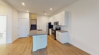 Located at 1810 Highpoint Ave in Richmond, Virginia, this two-story residence offers a clean, contemporary design with a thoughtful layout across both levels. The main floor centers around a well-appointed kitchen featuring stainless steel appliances — including a refrigerator, electric range, and built-in microwave — paired with crisp white cabinetry extending to the ceiling for ample storage. A kitchen island with an integrated sink and gray countertops provides additional workspace and seating. Light wood-style flooring flows throughout the main level, complementing the bright, open feel of the space. A staircase connects to the upper floor, where multiple bedrooms are finished with plush carpeting and natural light from windows fitted with blinds. Several bedrooms include walk-in or reach-in closets, offering generous storage. The bathrooms are finished in a clean, minimal style — one features large-format tile flooring, a tub-shower combination, and a well-lit vanity mirror, while another offers a white vanity with under-cabinet storage. Recessed lighting and neutral white walls throughout contribute to the home's bright and modern ambiance.