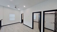 Located at 605 E 16th Street in Weslaco, Texas, this single-floor space showcases a striking modern design characterized by a crisp black-and-white color palette. The interior is unified by light wood-look flooring that runs throughout, providing a warm contrast to the bright white walls and bold black door frames, baseboards, and trim that define each room.

The layout, visible through a 3D scan, reveals a well-organized floor plan with multiple rooms connected by wide doorways framed in deep black molding. Recessed lighting illuminates the interiors throughout, complemented by ceiling fans with contemporary brushed nickel finishes in the living and bedroom areas. Windows dressed with white blinds allow natural light to filter in, maintaining the airy, open atmosphere.

A standout upper-level hallway features a sleek black metal railing overlooking a double-height open area below, adding architectural depth to the space. The bathroom is thoughtfully finished with white subway tile surrounding the tub and shower, a dark-cabinetry vanity with a white quartz countertop, and recessed lighting for a clean, polished look.

Overall, the space presents a cohesive, contemporary aesthetic with high-contrast design details and quality finishes throughout.