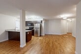 Located at 4623 199 Street NW in Edmonton, Alberta, this well-appointed one-bedroom, two-bathroom unit offers a thoughtfully designed single-floor layout with generous living space. Warm hardwood-style flooring flows throughout, creating a cohesive and inviting atmosphere. The open-concept kitchen and living area form the heart of the unit, with the kitchen showcasing rich dark cabinetry, light stone countertops, a stainless steel refrigerator, and black appliances, including a range and over-the-range microwave. A structural column adds an architectural detail that subtly defines the kitchen from the expansive living area, which is bathed in natural light from multiple windows. The bedroom offers a comfortable retreat with its own window, baseboard heating, a wall-mounted climate control unit, and a double-door closet for ample storage. Both bathrooms are clean and functional, each featuring a full soaker tub and shower combination with modern chrome fixtures. A dedicated in-suite laundry area houses a full-sized side-by-side washer and dryer, complete with overhead wire shelving. The hallway provides a practical transition between rooms, and the textured ceilings add a classic finish throughout the space.