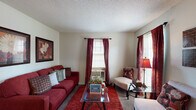 This single-floor, one-bedroom, one-bathroom residence in Memphis, Tennessee presents a practical and well-organized layout. The living room is a comfortable gathering space featuring carpet flooring, a textured ceiling, and multiple windows dressed with rich burgundy curtains that allow for natural light while maintaining privacy. A wall-mounted air conditioning unit provides climate control, and the room offers ample space for seating arrangements.

The kitchen is a galley-style space equipped with warm wood cabinetry, a double-basin sink, a coil-top electric range, and a full-size refrigerator. Light tile flooring and generous counter space make it functional for everyday use.

The bedroom is a well-proportioned retreat with soft carpet underfoot, a ceiling fan with integrated lighting, and windows with matching burgundy curtains that complement the overall color scheme. The room accommodates a full-size bed and additional furniture with ease, and a closet provides convenient storage.

The bathroom features a tiled tub-shower combination, a vanity with under-sink storage, a medicine cabinet with mirror, and tile wall surrounds that contribute to a clean, utilitarian finish. Throughout the unit, a consistent warm color palette ties each space together cohesively.