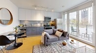 Located at 1051 Broughton Street in Vancouver's West End, this one-bedroom, one-bathroom unit offers a thoughtfully designed layout on a single floor. A light-filled hallway with light wood flooring leads from the entrance into the main living area, providing a clean and welcoming transition through the space.

The open-concept living and kitchen area forms the heart of the unit. The kitchen is outfitted with two-tone cabinetry — sleek white upper cabinets paired with slate-blue lower cabinets — complemented by a granite-style backsplash and stainless steel appliances including a refrigerator, stove, and microwave. Track lighting illuminates the kitchen, while the adjacent living area benefits from abundant natural light and direct access to a private balcony with outdoor seating and city views.

The spacious bedroom features floor-to-ceiling windows overlooking the surrounding Vancouver skyline and greenery, along with a sliding glass-panel closet that maximizes both storage and visual openness. Neutral tones and quality finishes give the room a calm, restful character.

The bathroom is finished with large-format floor tiles, white subway-style wall tiles surrounding the soaker tub and shower combination, and modern fixtures, creating a clean and functional space. Throughout, the unit maintains a consistent modern aesthetic with light wood flooring and a crisp white palette.