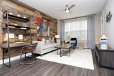 Located in the vibrant Grant Park neighborhood of Atlanta, Georgia, this single-floor residence offers a well-appointed layout with thoughtfully designed spaces throughout. The living room serves as a focal point of the home, anchored by a dramatic floor-to-ceiling reclaimed wood accent wall that adds warmth and texture. Light wood-style flooring, a ceiling fan, and large windows with patterned curtains contribute to a bright, contemporary atmosphere.

The kitchen is a standout feature, outfitted with stainless steel appliances including a French door refrigerator, electric range, over-the-range microwave, and dishwasher. Granite-style countertops, a subway tile backsplash, rich wood-toned cabinetry, open shelving, and a kitchen island complete the well-equipped space.

Multiple bedrooms provide varied and characterful retreats. One bedroom features a bold teal accent wall with stylish wall sconces and direct access to a bathroom. Another bedroom opens to the outdoors through floor-length glass doors framed by warm golden curtains, inviting abundant natural light. A third bedroom offers a more serene, neutral aesthetic with soft carpet and framed wall art.

Each bedroom is complemented by generously sized walk-in closets with built-in shelving and wire rack systems, offering ample storage. The overall design blends modern finishes with eclectic, curated styling throughout.