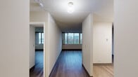 Located at 5441 N East River Rd in Chicago, IL, this two-bedroom, one-bathroom unit offers a practical and well-organized single-floor layout. Warm hardwood-style flooring runs throughout the unit, complementing the neutral-toned walls and creating a cohesive aesthetic from room to room.

The living room is an open, airy space with clean lines and room for a variety of furniture arrangements. A hallway connects the main living areas to the bedrooms and bathroom, with visible ventilation and lighting controls integrated into the walls.

The primary bedroom is a generously sized retreat featuring large windows that frame views of the surrounding Chicago cityscape, allowing natural light to fill the room throughout the day. A wide set of louvered bifold closet doors provides ample built-in storage. The second bedroom also benefits from large windows overlooking the city and greenery below, offering a bright and comfortable space.

The bathroom includes a full tub-shower combination with classic white square tile surround, offering a clean and timeless look.

Throughout the unit, the consistent flooring, neutral color palette, and abundant natural light from the oversized windows create a bright, functional living environment with pleasant urban views.