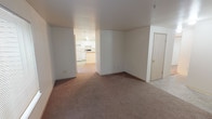 Located at 1015 112th St E, Unit B104, in Tacoma, Washington, this single-floor residence offers a practical and comfortable layout designed for everyday living. The open living area is finished with neutral-toned carpet throughout, creating a warm and cohesive feel across the main spaces. A window frames a view of an outdoor rock and greenery landscape, allowing natural light to fill the room with a calm ambiance.

The kitchen is efficiently designed in a U-shaped configuration, featuring white cabinetry with ample upper and lower storage, light-toned countertops, a double-basin sink, an electric range, and a dishwasher. Wood-look flooring in the kitchen provides a clean contrast to the carpeted living spaces.

The bedrooms are well-proportioned, each finished with plush carpet and equipped with baseboard heating. Several bedrooms include windows fitted with blinds that bring in natural light while maintaining privacy, with views of the surrounding exterior. One bedroom benefits from access to a closet and an adjoining bathroom, adding convenience.

A dedicated laundry area with washer and dryer hookups is visible within the unit, adding to the overall functionality of the space. The unit's clean, neutral palette and straightforward floor plan make it a versatile and move-in ready option in Tacoma.
