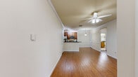 Located at 225 Sunlight Ln in Lake Mary, FL, this well-appointed one-bedroom, one-bathroom residence offers a comfortable and efficiently designed single-floor layout. The open-concept living and kitchen area serves as the heart of the home, featuring warm hardwood-style flooring, crown molding, and a ceiling fan with integrated lighting. Natural light streams in through large, blinds-fitted windows, creating a bright and welcoming atmosphere. The kitchen is outfitted with rich wood cabinetry, dark granite countertops, stainless steel appliances including a refrigerator, range, and microwave, and a wraparound breakfast bar that connects seamlessly to the living space. A pendant light above the bar adds a polished finishing touch. The bedroom offers a cozy retreat with plush carpeting, a ceiling fan, and a window with outdoor views. An adjacent closet provides dedicated storage. The bathroom is thoughtfully finished with a wood-toned vanity, dark granite countertop, a large mirror with overhead lighting, and a full tub-shower combination with tile surround. Two hallways connect the rooms, adding to the functional flow of the space. The neutral color palette and consistent design details throughout contribute to a cohesive, move-in-ready ambiance.
