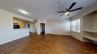 This single-floor residence offers a thoughtfully designed layout that balances open communal spaces with comfortable private quarters. The living area serves as the heart of the home, featuring rich, dark hardwood-style flooring, crown molding, and a ceiling fan with integrated lighting. A built-in shelving nook and a recessed desk area add functional character to the space, while a window allows natural light to fill the room. The front entryway opens directly into this living space, creating a welcoming first impression.

The kitchen is efficiently arranged with light wood cabinetry, generous counter space, and a full suite of black appliances including a refrigerator, range, and over-the-range microwave. The hardwood-style flooring continues seamlessly into this area, maintaining visual continuity throughout the common spaces.

Two carpeted bedrooms provide a soft, quiet retreat, each benefiting from natural light through sizable windows fitted with blinds. The primary bathroom features a dual-sink vanity with an L-shaped countertop, a large mirror, and hardwood-style flooring, offering an enhanced sense of space. A second full bathroom includes a single-sink vanity and a tub-shower combination, completing the functional layout of this well-balanced home.