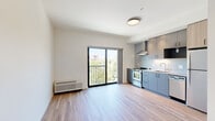 Located at 435 Alexander Loop in Eugene, Oregon, this efficiently designed one-bedroom, one-bathroom residence offers a well-planned layout across a single floor. The open living area features smooth wood-look flooring and crisp white walls that create a bright, clean atmosphere. A sliding glass door leads to a private balcony, filling the space with natural light and providing pleasant views of the surrounding greenery.

The kitchen is a standout feature, outfitted with sleek gray cabinetry, white quartz-style countertops, a textured tile backsplash, and stainless steel appliances including a gas range with a wall-mounted range hood and a dishwasher. Under-cabinet lighting adds both functionality and ambiance to this well-appointed cooking space.

The bedroom is a cozy, private retreat with the same warm wood-look flooring and a built-in closet with wire shelving, offering practical storage. A hallway connects the living areas to the bathroom, which features a wood-toned vanity with an undermount sink, white countertop, and a combination tub and shower. Accessibility-friendly grab bars and neutral tones give the bathroom a clean, modern feel.

Throughout the unit, the design prioritizes clean lines, neutral tones, and functional use of space, making it a comfortable and contemporary home in Eugene.