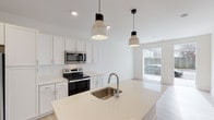 Located at 2420 Concord St in Cincinnati's 45206 neighborhood, this single-floor unit offers a clean, contemporary design highlighted by a bright, all-white interior and light-toned luxury vinyl plank flooring that runs throughout the space. The open-concept kitchen serves as the centerpiece of the unit, featuring crisp white shaker cabinetry extending to the ceiling for ample storage, light quartz countertops, and a large center island with an undermount stainless steel sink and stylish pendant lighting overhead. A full suite of stainless steel appliances — including a refrigerator, electric range, and over-the-range microwave — provides a polished, move-in-ready kitchen experience. The kitchen flows seamlessly into the living area, which benefits from natural light courtesy of a large window with exterior views. A notable convenience feature is the in-unit stacked washer and dryer, neatly tucked behind a dedicated closet door adjacent to the kitchen. The bathroom is well-appointed with white shaker-style vanity cabinetry, a quartz countertop, a large mirror, and a full tub-shower combination. Recessed lighting throughout the unit ensures consistent, functional illumination, while the cohesive white-and-neutral palette creates a fresh, modern ambiance ideal for comfortable everyday living.