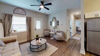 Located at 506 Williams St in Grovetown, Georgia, this single-story residence showcases a cohesive modern farmhouse aesthetic throughout. Rich wood-look flooring flows seamlessly across the open living areas, anchoring the warm, neutral color palette found in every room.

The living room offers a welcoming layout with a ceiling fan, abundant natural light from front-facing windows, and direct access to the front entry. The space comfortably accommodates multiple seating arrangements, making it ideal for relaxing or entertaining.

The kitchen is a functional highlight, featuring white shaker-style cabinetry with matte black hardware, granite-style countertops, a stainless steel appliance suite including a refrigerator, range, microwave, and dishwasher, and a deep sink with a contemporary faucet. Ample cabinet storage and counter space make this kitchen as practical as it is attractive.

Both bedrooms are generously sized with ceiling fans, natural light from windows, and continued wood-look flooring. Each offers comfortable proportions and well-defined spaces.

The two bathrooms mirror each other in design, each offering white vanity cabinetry, granite-topped counters, a tub-shower combination, and wood-look flooring. A dedicated laundry room with built-in shelving and washer/dryer hookups rounds out this well-planned home.