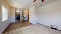 This single-floor residence offers a thoughtfully designed layout that balances comfort and functionality. The open-concept living area is anchored by plush carpeting and a ceiling fan with integrated lighting, while multiple windows dressed with horizontal blinds invite generous natural light and outdoor views. A glass door provides convenient exterior access directly from the living space.

The kitchen is efficiently arranged with warm wood-toned cabinetry, granite-style countertops, and black appliances including a full-size refrigerator, electric range, and built-in microwave. A breakfast bar peninsula connects the kitchen to the living area, enhancing the open flow of the space. Durable wood-look flooring runs throughout the kitchen for easy maintenance.

A central hallway connects the private areas of the residence, including multiple carpeted bedrooms, each featuring neutral walls and windows with outdoor views. The bedrooms offer a calm, versatile atmosphere well-suited to a variety of uses.

The bathrooms are finished with light tile flooring, wood-toned vanity cabinetry, granite-style countertops with brushed nickel hardware, and walk-in shower areas. Clean, neutral tones throughout create a bright and cohesive aesthetic across the entire space.