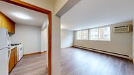 Located at 6301 Lyndale Ave S in Richfield, MN, this one-bedroom, one-bathroom unit offers a practical and well-organized layout across a single floor. The living room is the largest area of the home, featuring light-toned hardwood-style flooring, neutral walls, and a wide bank of windows that draw in natural light and provide views of the surrounding neighborhood. A wall-unit air conditioner and baseboard heating ensure year-round comfort. Warm-toned wood door frames and trim provide a consistent design element throughout the space. A hallway connects the main living area to the private bedroom and bathroom, offering a clear and functional flow. The bedroom is a comfortable, well-proportioned room finished with plush carpet, a window with natural light, and baseboard heating. Two doors in the bedroom provide access to a closet and the hallway. The kitchen, visible in the dollhouse view, includes wood-toned cabinetry and white appliances. The bathroom is thoughtfully updated, featuring a soaking tub with a marble-style tile surround, brushed nickel hardware and grab bars, a vanity with a white countertop, and wood-look flooring that ties the space together with warmth and practicality.
