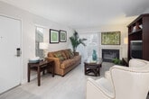 Located at 27111 Traminer Terrace in Laguna Niguel, California, this single-floor apartment offers a thoughtfully designed layout with comfortable living spaces throughout. The living room serves as the heart of the home, featuring light wood-style flooring, a classic fireplace with a marble-style surround, and a large sliding glass door with vertical blinds that allows abundant natural light to fill the space. Adjacent to the living area, the dining space provides an intimate setting with a round glass-top table, a statement pendant light, and a large mirror that enhances the sense of openness. The kitchen is outfitted with sleek white cabinetry, light countertops, stainless steel appliances including a full-size refrigerator, gas range, and built-in microwave, along with a distinctive tray ceiling with recessed lighting that adds architectural interest. The bedroom is a serene retreat with plush carpeting, multiple windows that invite natural light, and convenient access to a walk-in closet. The bathroom features a full tub and shower combination with a curved curtain rod. Throughout the apartment, neutral tones and clean finishes create a cohesive and welcoming ambiance, ideal for comfortable everyday living in the heart of Laguna Niguel.
