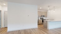 Located at 2964 Route 9W in Saugerties, NY, this single-floor residence showcases a clean, contemporary design with a cohesive neutral palette throughout. Light-toned luxury vinyl plank flooring runs through the main living areas, complementing the bright white walls and recessed lighting that create an airy, well-lit atmosphere.

The open-concept living and kitchen area serves as the heart of the unit. The kitchen is equipped with a full suite of stainless steel appliances, including a refrigerator, electric range, and over-the-range microwave. Light wood-tone cabinetry with sleek bar-pull hardware extends from floor to ceiling, offering generous storage. A peninsula with a white quartz countertop and integrated sink separates the kitchen from the living space, with pendant lighting overhead adding a stylish focal point.

The living area is spacious and open, with multiple windows allowing natural light to filter in from the exterior. The bedroom features soft carpeting underfoot and a large window with views of the surrounding greenery, contributing a calm, residential feel.

Two bathrooms serve the unit — one featuring a soaking tub-shower combination, and the other a standalone walk-in shower. Both share matching light wood vanities with white countertops and wood-look flooring. An in-unit laundry area with stacked washer and dryer hookups adds everyday convenience to this thoughtfully designed space.