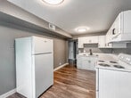 Located at 1 Avon Ave in Williamsburg, Virginia, this single-floor home presents a clean, modern aesthetic throughout its well-organized layout. The interior is unified by a contemporary gray color palette, with crisp white trim and baseboards providing a sharp contrast that lends each room a polished, cohesive look.

The living area features smooth vinyl plank flooring in a warm wood tone, offering both durability and visual warmth. The open feel of the space is enhanced by neutral gray walls and multiple doorways that connect seamlessly to adjacent rooms, promoting an easy flow throughout the home.

The kitchen is equipped with white cabinetry offering ample storage, light countertops, and a white electric range with overhead ventilation. The same vinyl plank flooring extends through the kitchen, maintaining a consistent and practical finish. The generous wall space provides flexibility for additional furnishings or appliances.

The bedrooms are finished with plush wall-to-wall carpeting in a neutral gray tone, creating a comfortable and quiet retreat. Each bedroom benefits from natural light, with one featuring a window fitted with horizontal blinds. The rooms offer a versatile, move-in-ready canvas suitable for a variety of arrangements.

Overall, this Williamsburg home combines functional design with clean, contemporary finishes, making it a practical and inviting single-floor residence.
