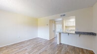 Located at 744 Spring West Rd in Orlando, Florida, this single-floor unit offers a clean, functional layout with consistent finishes throughout. The open living area is finished with light wood-look flooring, neutral cream-toned walls, and a textured ceiling, creating a bright and airy atmosphere. Natural light filters in through a large window fitted with vertical blinds, illuminating the spacious main living space. A front entry door provides direct access to the unit.

The kitchen is positioned adjacent to the living area, separated by a peninsula-style breakfast bar topped with granite countertops. White cabinetry lines the upper walls, complemented by a gas range and ample counter space, making the kitchen both practical and visually cohesive.

The bedroom features plush carpeting underfoot and benefits from a full sliding glass door fitted with vertical blinds, offering views of the outdoors and generous natural light. Built-in shelving adds convenient storage within the room.

The bathroom is thoughtfully appointed with matching granite countertops on a white vanity with brushed nickel hardware, wood-look tile flooring, and a full soaking tub with shower combination. The space maintains a clean, neutral palette throughout, offering a move-in ready environment in a convenient Orlando location.