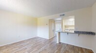 Located at 744 Spring West Rd in Orlando, Florida, this single-floor unit offers a clean, functional layout with consistent finishes throughout. The open living area is finished with light wood-look flooring, neutral cream-toned walls, and a textured ceiling, creating a bright and airy atmosphere. Natural light filters in through a large window fitted with vertical blinds, illuminating the spacious main living space. A front entry door provides direct access to the unit.

The kitchen is positioned adjacent to the living area, separated by a peninsula-style breakfast bar topped with granite countertops. White cabinetry lines the upper walls, complemented by a gas range and ample counter space, making the kitchen both practical and visually cohesive.

The bedroom features plush carpeting underfoot and benefits from a full sliding glass door fitted with vertical blinds, offering views of the outdoors and generous natural light. Built-in shelving adds convenient storage within the room.

The bathroom is thoughtfully appointed with matching granite countertops on a white vanity with brushed nickel hardware, wood-look tile flooring, and a full soaking tub with shower combination. The space maintains a clean, neutral palette throughout, offering a move-in ready environment in a convenient Orlando location.