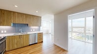 Located at 1150 E Street in San Diego's vibrant East Village, this three-bedroom, three-bathroom residence offers a well-designed layout across a single floor. Light hardwood flooring flows throughout the space, complementing a clean, modern aesthetic defined by white walls and abundant natural light.

The kitchen is a standout feature, outfitted with warm wood cabinetry, white quartz countertops, a subway tile backsplash, and a full suite of stainless steel appliances including a refrigerator, range, microwave, and dishwasher. It opens toward the combined dining and living area, which is bathed in natural light from large floor-to-ceiling windows offering sweeping views of the San Diego skyline and surrounding cityscape. A balcony extends the living space outdoors, providing direct access to those panoramic views.

The three bedrooms are bright and well-proportioned, each featuring hardwood flooring and generous closet space. The primary bedroom includes access to natural light through large windows. The three bathrooms are finished with marble-style tile on both the floors and shower surrounds, paired with soaking tubs and chrome fixtures for a clean, refined look. Additional conveniences include in-unit laundry and multiple closets throughout. This residence combines contemporary finishes with an elevated high-rise setting in the heart of San Diego.
