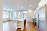 Located at 2500 Vantage Dr in Woodbridge, VA, this well-appointed 2-bedroom, 3-bathroom home offers a thoughtfully designed single-floor layout. The open-concept living, dining, and kitchen area serves as the heart of the home, bathed in natural light from large, wrap-around windows that offer outdoor views. The kitchen is outfitted with stainless steel appliances, white upper cabinetry, a tile backsplash, dark lower cabinets, and a central island with a white quartz countertop and built-in shelving — ideal for both cooking and casual dining. Warm hardwood-style flooring flows throughout the main living areas, complemented by recessed lighting overhead. The bedrooms feature plush carpeting, ceiling fans, and windows that frame natural greenery. The primary bedroom is generously sized and includes a walk-in closet with extensive wire shelving for organized storage. The bathrooms are finished with clean, modern fixtures, including a tiled soaking tub and shower combination, a floating vanity with a white countertop, and hardwood-style flooring. Additional spaces include a combined bathroom and laundry room, a utility room, and multiple closets throughout, ensuring ample storage across the entire home.