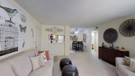 This single-floor residence offers a thoughtfully arranged layout that maximizes comfort and functionality throughout. The open-concept living and dining area forms the heart of the home, featuring soft carpeting, neutral walls, and a textured ceiling. The living space provides a welcoming atmosphere, while a pass-through window connects seamlessly to the kitchen, enhancing the sense of openness. A ceiling fan with light fixture serves the dining area, which comfortably accommodates a dining table and chairs.

The galley-style kitchen is efficiently designed with warm wood cabinetry, white appliances including a refrigerator, electric range, and over-the-range microwave, as well as tile flooring and ample counter space. A doorway from the kitchen provides direct access to the dining area, creating a practical flow for everyday living.

The bedroom is a restful retreat, complete with plush carpeting, a ceiling fan with integrated lighting, and a walk-in closet that offers generous storage. The full bathroom features a single-sink vanity with a large mirror, Hollywood-style lighting, and a tub and shower combination with tile surround. A dedicated laundry area includes built-in shelving for additional storage and washer/dryer hookups, adding a convenient and practical finishing touch to this well-rounded home.