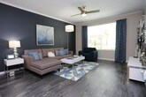 Located at 116 Juniper St NE in Atlanta's vibrant Old Fourth Ward neighborhood, this single-floor residence offers a well-designed layout with modern finishes throughout. Dark hardwood-style flooring flows through the main living areas, creating a cohesive and contemporary aesthetic.

The kitchen is a standout feature, outfitted with crisp white cabinetry, granite countertops, and stainless steel appliances including a range, microwave, and refrigerator. A peninsula with seating for multiple bar stools and pendant lighting above serves as both a functional workspace and a casual dining area, seamlessly connecting the kitchen to the rest of the open living space.

The living room features crown molding, a bold dark accent wall, a ceiling fan, and a large window that invites natural light and outdoor views. Adjacent to the living area, the dining space accommodates a round glass table and opens toward the kitchen peninsula.

The bedroom is carpeted and generously sized, offering a ceiling fan, a natural-light window with outdoor views, and multiple closet doors providing ample storage. The bathroom continues the granite and white cabinetry theme, featuring a wide vanity with a framed mirror and stylish fixtures. Overall, the space presents a clean, modern ambiance suited to comfortable everyday living.