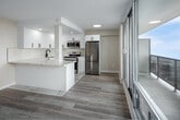 Located on the 19th floor at 22 Close Ave in Toronto's vibrant Parkdale neighbourhood, this one-bedroom, one-bathroom unit offers an efficiently designed layout making excellent use of its compact footprint. The open-concept living area is anchored by floor-to-ceiling windows and a glass-railed balcony, framing dramatic panoramic views of Lake Ontario and the Toronto skyline—a defining feature of the space. Light hardwood flooring runs throughout, complementing the neutral warm-toned walls and contributing to a bright, airy atmosphere. A wall-mounted air conditioning unit serves the living area.

The kitchen is a standout, showcasing crisp white cabinetry with matte black hardware, striking marble-look quartz countertops and matching flooring, a subway tile backsplash, and a full suite of stainless steel appliances including a dishwasher. A peninsula provides additional prep space and casual seating potential.

The bedroom is a comfortable size, fitted with a sliding double closet and a dedicated window offering city views and natural light. The bathroom features a full soaker tub and shower combination with clean white subway tile surround and chrome fixtures, maintaining the unit's consistent modern aesthetic throughout.