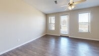 Located at 4001 De Morada Dr in Odessa, Texas, this single-floor unit offers a thoughtfully designed layout that maximizes every square foot. The open-concept living and kitchen area forms the heart of the space, creating a seamless flow between daily living and cooking. The kitchen is outfitted with crisp white shaker-style cabinetry, granite-look countertops, a subway tile backsplash, and a full suite of stainless steel appliances, including a range, microwave, dishwasher, and refrigerator. The living area benefits from natural light streaming through a large window and a glass exterior door, complemented by a ceiling fan with integrated lighting. Neutral beige walls and durable wood-look flooring run throughout the entire space, lending a clean, cohesive aesthetic. The bathroom features a white vanity with a granite-look countertop, a large mirror, and consistent wood-look flooring, maintaining the modern finish found throughout the unit. A dedicated closet provides practical storage. The overall ambiance is bright, clean, and functional, reflecting a contemporary design sensibility suited for comfortable everyday living.