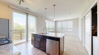 Located at 291 Graceland Blvd in Columbus, OH, this one-bedroom, one-bathroom residence offers a thoughtfully designed single-floor layout. The open-concept living area seamlessly connects the kitchen, dining, and living spaces, creating a bright and functional environment. The kitchen is a standout feature, anchored by a granite-topped island with a built-in sink and stainless steel dishwasher. Dark espresso cabinetry, a subway tile backsplash, stainless steel appliances — including a refrigerator, range, and microwave — and dual pendant lights with track lighting complete the space. Wood-style flooring runs through the kitchen and flows into the carpeted living and dining area, where large windows and a sliding glass door flood the room with natural light and provide access to a private balcony with outdoor views. The bedroom is a comfortable retreat featuring plush carpet, a large window, and neutral tones. The bathroom includes a dark wood vanity with a stone countertop, wood-style flooring, and access to a walk-in closet with wire shelving. A second closet provides additional storage, and an in-unit laundry area adds everyday convenience.