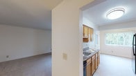 This single-floor residence offers a clean, functional layout designed for comfortable everyday living. The kitchen is efficiently organized with warm oak cabinetry, dark countertops, tile flooring, and black appliances including a refrigerator and dishwasher. A stainless steel sink sits beneath a window, allowing natural light into the space. The kitchen connects seamlessly to the main living area through an open archway, creating a cohesive flow between spaces.

The living room is generously proportioned, featuring soft wall-to-wall carpeting, a ceiling fan with light fixture, and a private entrance door. Adjacent to the living area, a bright bedroom benefits from two large windows dressed with vertical blinds, offering pleasant outdoor views of surrounding greenery.

A second bedroom provides a quiet, carpeted retreat with ceiling ventilation and ample wall space. This room is complemented by a spacious walk-in closet outfitted with wire shelving and hanging rods along multiple walls, offering exceptional storage capacity.

The bathroom is neatly appointed with tile flooring, a single-sink vanity with oak cabinetry, an overhead medicine cabinet, and a full tub-shower combination with white tile surround and chrome fixtures. Bright white walls and clean finishes give the bathroom a fresh, well-maintained appearance throughout.