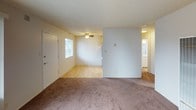 This upstairs one-bedroom, one-bathroom unit is thoughtfully laid out across a single floor, offering a comfortable and functional living environment. The living area features plush carpeting and a large window dressed with vertical blinds, allowing natural light to fill the space. A ceiling fan adds both comfort and style to the adjoining area near the entry, which transitions to easy-care hardwood-style flooring. The kitchen is efficiently designed with warm honey-toned cabinetry extending to the ceiling for ample storage, white countertops, a stainless steel sink, and black appliances including a gas range and full-size refrigerator — all finished with matching hardwood-style flooring. The bedroom is generously sized, featuring soft carpeting, neutral white walls, and a textured ceiling, providing a quiet and restful retreat. The bathroom is clean and bright, appointed with a white vanity, wood-style flooring, and a full tub and shower combination enclosed by sliding glass doors, with a frosted window above for natural light and privacy. Throughout the unit, a neutral color palette and textured ceilings create a cohesive, move-in-ready atmosphere.