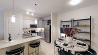 Located on Bonnar Bridge Pkwy in Burlington, NC, this single-floor residence offers a thoughtfully designed layout with modern finishes throughout. The open-concept kitchen is a standout feature, showcasing gray shaker-style cabinetry, granite countertops, stainless steel appliances, a built-in wine rack, and a peninsula island with bar seating — all illuminated by stylish pendant lighting. The kitchen flows seamlessly into a dedicated dining area, making it ideal for both everyday living and entertaining. The living room is characterized by a bold green accent wall, a ceiling fan, track lighting, and large windows that invite an abundance of natural light. The bedroom features plush carpeting, multiple windows with blinds and draping curtains, a ceiling fan, and generous closet space, creating a calm and restful retreat. Two full bathrooms are finished with granite-topped gray vanities and tile flooring. The first includes a walk-in shower with a curtained enclosure and a window for natural light, while the second offers a vanity and toilet in a clean, neutral palette. Throughout the residence, light-toned flooring, neutral walls, and consistent quality finishes contribute to a cohesive and welcoming atmosphere.