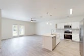 Located at 4781 SW 36 Rd in Gainesville, FL, this single-story, 3-bedroom, 2-bathroom home offers a thoughtfully designed open-concept layout. Light-toned luxury vinyl plank flooring flows throughout, lending a clean, cohesive look to the entire space. The heart of the home is a combined living, dining, and kitchen area filled with natural light. The kitchen features white shaker-style cabinetry, quartz countertops, a subway tile backsplash, stainless steel appliances including a range, microwave, and dishwasher, and a center island with a sink and pendant lighting overhead. The living area is spacious and airy, highlighted by a ceiling fan and French doors that open to views of the outdoors. Three well-proportioned bedrooms each include ceiling fans and ample natural light from large windows. The primary bedroom connects to a walk-in closet. The bathrooms are well-appointed, with one featuring a soaking tub and tiled surround. A dedicated laundry room houses a full-size washer and dryer. Additional storage is provided through four closets and a utility room. The home's bright, neutral palette and modern finishes create a clean, move-in-ready atmosphere throughout.