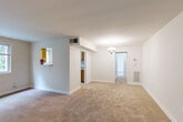 Located at 8810 Lanier Dr in Silver Spring, Maryland, this two-bedroom, one-bathroom residence offers a practical and comfortable single-floor layout. The combined living and dining area serves as the heart of the home, featuring warm neutral carpet, a classic chandelier, and a large multi-pane window that frames lush green outdoor views, filling the space with natural light. A pass-through window connects the living area to the kitchen, adding an open, communicative feel between the spaces.

The kitchen is outfitted with warm wood cabinetry, light countertops, tile flooring, and a full suite of white appliances including a range, microwave, dishwasher, and refrigerator. A window over the sink brings in additional natural light and garden views.

The primary bedroom is generously sized, carpeted, and finished with neutral tones that create a calm, restful atmosphere. The second bedroom also features carpet flooring and a window overlooking greenery, offering a bright and versatile space suitable for a guest room or home office. The full bathroom features tile flooring and a functional vanity layout.

A central hallway connects the rooms efficiently, and the residence benefits from four closets throughout, providing ample storage. The unit's entry is marked by a distinctive green door, adding a touch of character to this well-laid-out Silver Spring home.