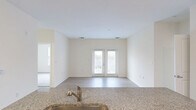 Located at 1351 Sapphire Dr in Virginia Beach, VA, this well-appointed two-bedroom, two-bathroom residence offers a thoughtfully designed single-floor layout with a clean, modern aesthetic throughout. The open-concept living and kitchen area is a central highlight, featuring a granite-topped island with a stainless steel sink, dark cabinetry with brushed hardware, and light hardwood-style flooring that extends through the main living space. The living area is bright and airy, benefiting from natural light that pours in through a set of double French doors leading to the outdoors. The kitchen corridor provides additional counter and cabinet space, enhancing functionality. Both bedrooms are carpeted for comfort, with the spacious primary bedroom offering a generous walk-in closet equipped with wire shelving for organized storage. The two bathrooms include a tiled bath with a shower-tub combination. A dedicated in-unit laundry room houses a full-size side-by-side washer and dryer with overhead shelving. Neutral, warm tones throughout the home create a cohesive and inviting atmosphere, making this Virginia Beach residence a practical and comfortable living space.