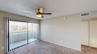 Located at 5215 West Peoria Avenue in Glendale, Arizona, this one-bedroom, one-bathroom unit offers a thoughtfully organized single-floor layout. The combined kitchen and living area forms the heart of the home, where light wood-look flooring flows through the kitchen while plush carpet extends across the living space. The kitchen is outfitted with white shaker-style cabinetry, light quartz countertops, a peninsula with a sink, and a full suite of stainless steel appliances including a refrigerator, range, microwave, and dishwasher. A textured ceiling and recessed lighting complete the space. The living room opens directly to an outdoor patio through a sliding glass door with vertical blinds, offering views of what appears to be a pool area — a bright, airy connection to the outdoors. A ceiling fan with a light fixture adds both comfort and function to this space. The bedroom is carpeted and features a window with natural light, a textured ceiling, and access to a dedicated walk-in closet equipped with multiple shelving rods for organized storage. The bathroom includes a full tub-shower combination with chrome fixtures. A hallway connects the main areas of the unit, contributing to an efficient and functional flow throughout.